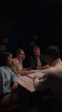 Genç bayan takım lideri gülümseyen genç meslektaşlarına şirket geliştirme stratejisini anlatıyor. Mutlu iş adamları akşam ofisinde birlikte çalışmaktan zevk alırlar. 