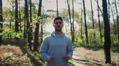 Jogging male fitness model working out training for marathon on forest road in amazing nature landscape.. Runner man sprinting workout on forest road