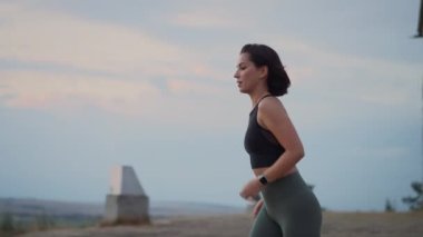 Young fitness woman runner checking time from smart watch. Young woman checking heart rate while jogging on summer hill