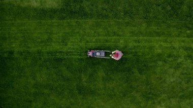 Professional lawn care service. Top view of man mowing green grass in modern garden with lawn mower. Unknown man using lawn mower in the backyard