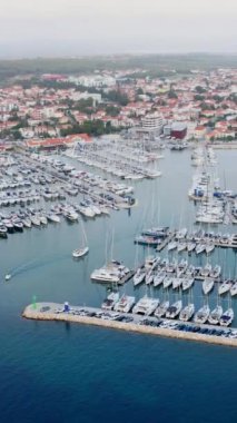 Güzel körfezdeki iskeledeki birçok yelkenlinin dikey hava görüntüsü. Yelkenli limanı, limanda demirli yelkenli yatlar. Modern su taşımacılığı, yaz tatili, lüks yaşam tarzı ve...