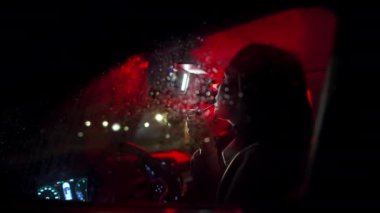 Esmer iş kadını aynaya bakıyor ve geceleri açık renkli arabasıyla makyaj yapıyor. Halk yaşam tarzı konsepti.