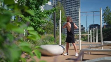 Bronzlaşmış güçlü bir adam sabah koşusundan önce dışarı çıkıyor. Yakışıklı sakallı bir erkek sokak parkında egzersiz yapıyor ve ısınıyor.