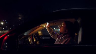 Dikkati dağılmış sürücü. Genç çekici bir kadın aynaya bakıyor dudaklarını boyuyor geceleri arabada otururken makyaj yapıyor.