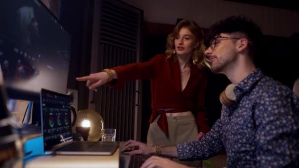 两名积极的男同事和女同事在总部进行3D设计 快乐的女士帮助男人在电脑上建模 在大型计算机监视器上创建电子游戏人脸的时尚团队 — 图库视频影像