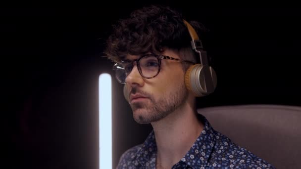 Lockigt Glasögon Man Bär Hörlurar Stirrar Bildskärm När Arbetar Online — Stockvideo