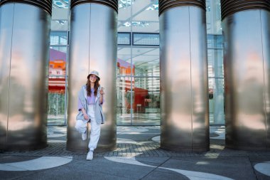 Akıllı telefon tutan, modern binanın önünde kameraya poz veren şık, güzel bir modelin portresi. Metin mesajları gönderiliyor. . 