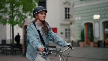 Avrupa 'nın şehir sokağında bisiklet süren kasklı ciddi bir kız. Yaz yolculuğunda bisiklet kullanarak gülümseyen genç kadın yaşam tarzı, ECO dostu. 