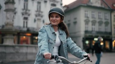 Yolculuğunun tadını çıkarıyor. Güzel bir kadının belden yukarı portre görüntüsü. Bisiklete biniyor ve gülümsüyor.