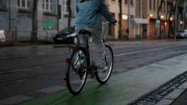 Gece lambaları caddesinde bisiklet süren genç bir kadının dikiz aynası. Yazın bisiklet süren aktif bir kız. Çevre dostu ulaşım konsepti