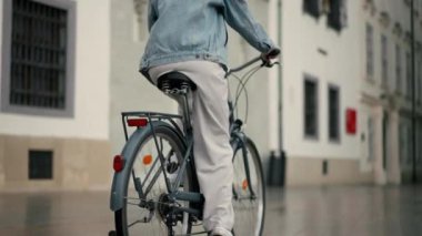 Kırpılmış manzaralı kız Avrupa 'nın şehir sokağında bisiklet sürüyor. Yaz yolculuğunda bisiklet kullanan genç kadın yaşam tarzı, ECO dostu.