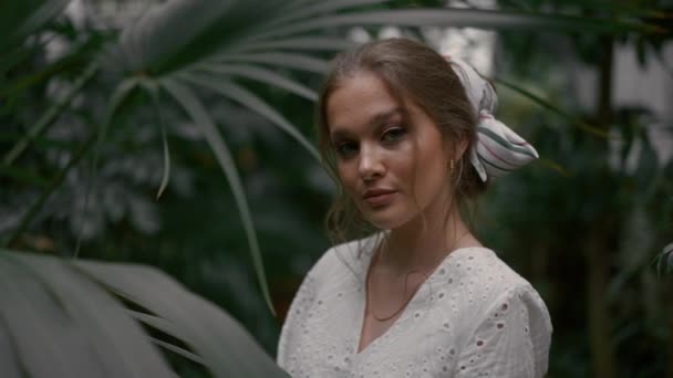 柔らかい顔をした植物園の美しい若い女性 パームと緑の木が囲まれている 肌は白く 落ち着いた顔 自然な美しさ — ストック動画