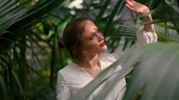 植物園の緑の木 草に囲まれた庭に立っている白いドレスを着た長い髪の美しい女性 自然と人々のコンセプト — ストック動画
