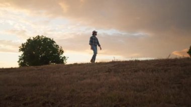 Çiftçinin gün batımında buğday tarlasında yürüyüp tadını çıkarışını tam uzunlukta görebiliyoruz. Tarım kavramı
