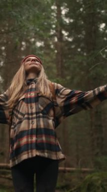 Happy woman raised arms in the forest, closed eyes, enjoying fresh air and amazing nature. Hiking, hobby, relaxation, recreation time concept