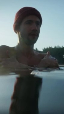 Caucasian bearded man immersing in icy water on winter day. Male person leading healthy lifestyle at the forest. Winter swim and cold treatment concept