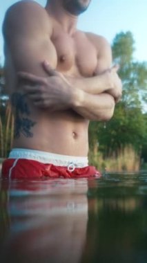 Frozen man plunges into icy water at morning. Male person chills and shakes inside cold winter lake at forest. Winter swim concept