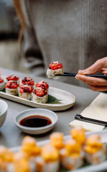 Eating sushi with chopsticks close up, food takeout and delivery service, salmon sushi rolls, tasty meal, sushi delivery. High quality photo