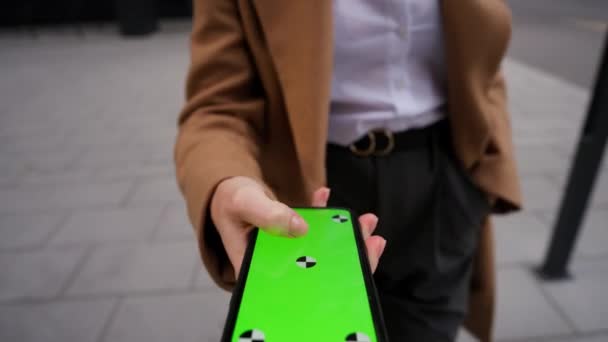 年轻女子手牵着手机 与绿色屏风垂直地在街上走来走去 互联网技术概念 — 图库视频影像