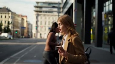 Gündüz vakti modern binanın yanından geçerken elinde cep telefonu olan ve mesaj okuyan beyaz gömlekli genç bir iş kadını. Halk yaşam tarzı konsepti 