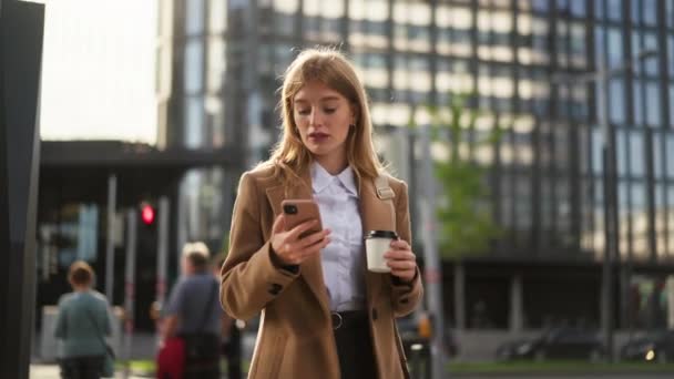 市街地の携帯電話を使用してコーヒーカップでジャケットで若い笑顔ビジネス女性 — ストック動画