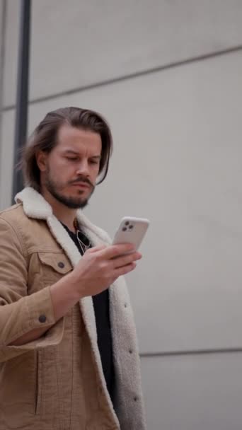 在城市散步时 活跃的商人一边忙着在智能手机上打字一边发短信 白人男子正在观看移动设备穿过空旷街道的地图 — 图库视频影像