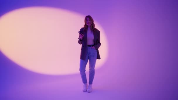 快乐聪明快乐的年轻女性使用手机 透过紫罗兰色的墙壁背景看相机 技术和人的概念 — 图库视频影像