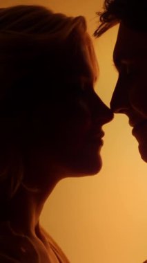 Romantik bir randevu sırasında, parlak turuncu neon ışığı altında öpüşen genç bir çift. Duygular konsepti