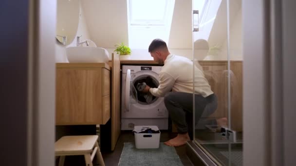 Junger Mann Lädt Kleidung Waschmaschine Badezimmer Ernsthafter Kerl Macht Hausroutine — Stockvideo
