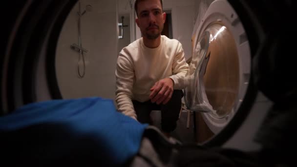 Серйозний Чоловік Відкриває Пральну Машинку Приймає Чистий Одяг Вдома Вид — стокове відео