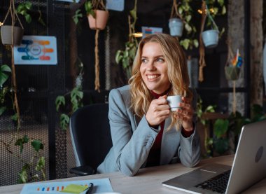 Yeşil Bitkiler 'in ofisindeki son sınıf öğrencisinin portre görüntüsü kameraya yansıyor. Olgun iş adamı modern ofiste masada tek başına kameraya bakıyor.