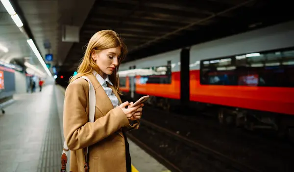 Nuori Pitkätukkainen Nainen Messaging Puhelin Seisoessaan Metrossa Maanalainen Metro Alustan — kuvapankkivalokuva
