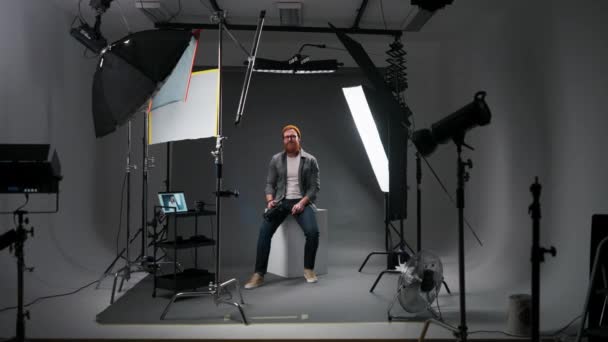 フォトカメラを持ち 照明機器を搭載したスタジオで撮影した写真を撮った後 笑顔の写真家 職業コンセプト — ストック動画