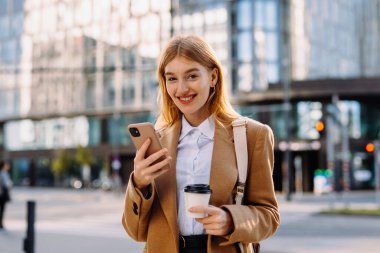 Bir kadın bir fincan kahve tutuyor ve kameraya bakıyor. Yüksek kalite