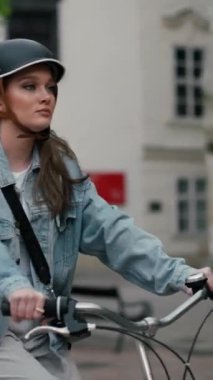 Avrupa 'nın şehir sokağında bisiklet süren kasklı ciddi bir kız. Yaz yolculuğunda bisiklet kullanarak gülümseyen genç kadın yaşam tarzı, ECO dostu. 