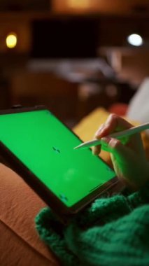 Kişi yeşil ekranlı bir tablet ve ahşap bir masa üzerinde bir stil kullanıyor, çimenli bir açık hava etkinliğinde sanat yaratıyor. Makro fotoğrafçılık, çalışmalarının karmaşık detaylarını yakalar.