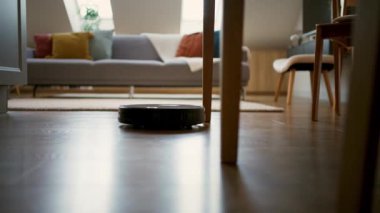 Robot elektrikli süpürge odada yerleri süpürüyor. Hayatı basitleştiren otomatik cihazları olan akıllı bir ev. Akıllı bir elektrikli süpürge yerleri temizler.