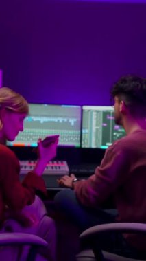 Müzik stüdyosunda ses mühendisiyle çalışırken elinde akıllı telefon ve şarkı tutan yaratıcı bir kadın. İki meslektaş karışık program yazılımını kullanarak güzel bir şarkı yaratıyor. Yaratıcı sanatçılar
