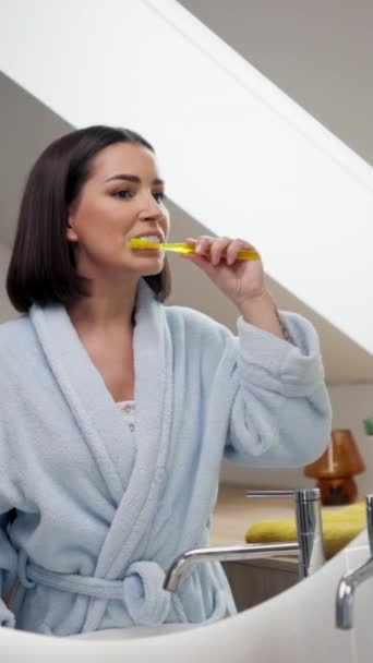 Uma Mulher Senta Frente Espelho Banheiro Escovando Dentes Com Uma — Vídeo de Stock