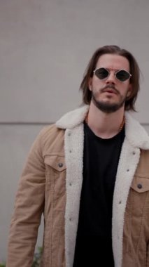 Şehir sokağında poz veren yakışıklı bir delikanlı. Yüzünde ciddi bir ifade var. Şık görünümlü çekici erkek hipster modeli.