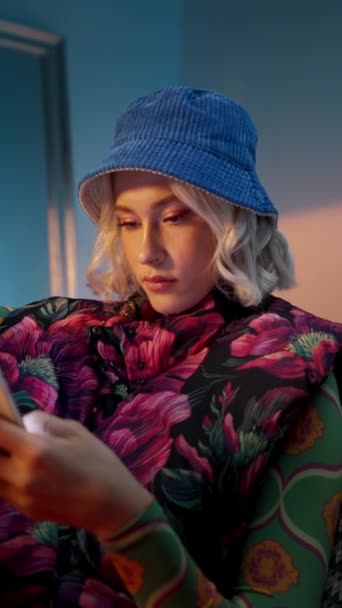 时尚的女人坐在扶手椅上 晚上在工作室的智能手机上浏览互联网 — 图库视频影像