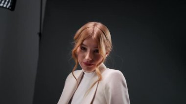 Stüdyoda poz veren güzel kadın modelin portresi siyah arka planda yanıp sönüyor. Sandalyede oturan sarışın kız. Modellik konsepti