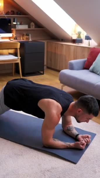 一个男人在客厅里的瑜伽垫上做着一块木板 他的胳膊 胸部和心窝都被固定住了 以保持身体的稳定和力量 同时他的膝盖和大腿也从木制地板上移开 以求得安慰 视频剪辑
