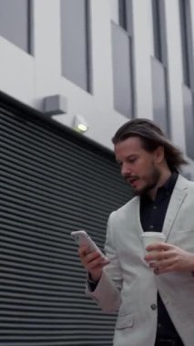 Genç beyaz bir adam akıllı telefonuyla sohbet ediyor. İş adamı mesaj yazıyor ve sanayi binasının yakınında yürüyor. Yönetici molada kahve içiyor.
