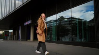 Keyifli stil sahibi bir iş kadını iş molasında mutlu ve zıplıyor. Portre muhteşem emlakçı sokakta geziniyor ve yukarı bakıyor.
