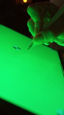 Yeşil ekranlara ve yüzeylere yeşil ekranlı tablet de dahil olmak üzere kalemle yazı yazan birini gösteren bir video. Odak noktası yazma ve yaratıcılık yüksek kalite