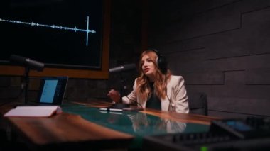 Dijital kayıt stüdyosunda çalışırken mikrofon kullanan kulaklıklı genç bir kadın. Mesleki meslek kavramı