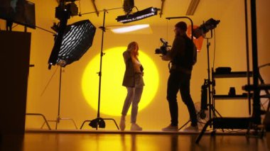 Dansçı bayanın sarı arka planlı videosunu çeken sakallı operatörün geniş açılı görüntüsü. Olay içinde fotoğrafçı video kaydı etkinliği