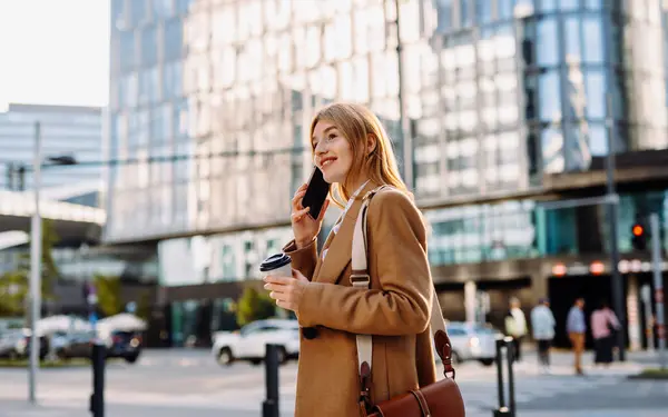 Konzentrierte Geschäftsfrau Die Smartphone Hintergrund Der Stadt Spricht Ernsthafte Berufstätige lizenzfreie Stockfotos