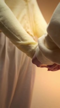 Birkaç el. Açık renkli elbiseli kadın ve erkeğin bej renkli stüdyo arka planında el ele tutuşmaları. Şehvet kavramı